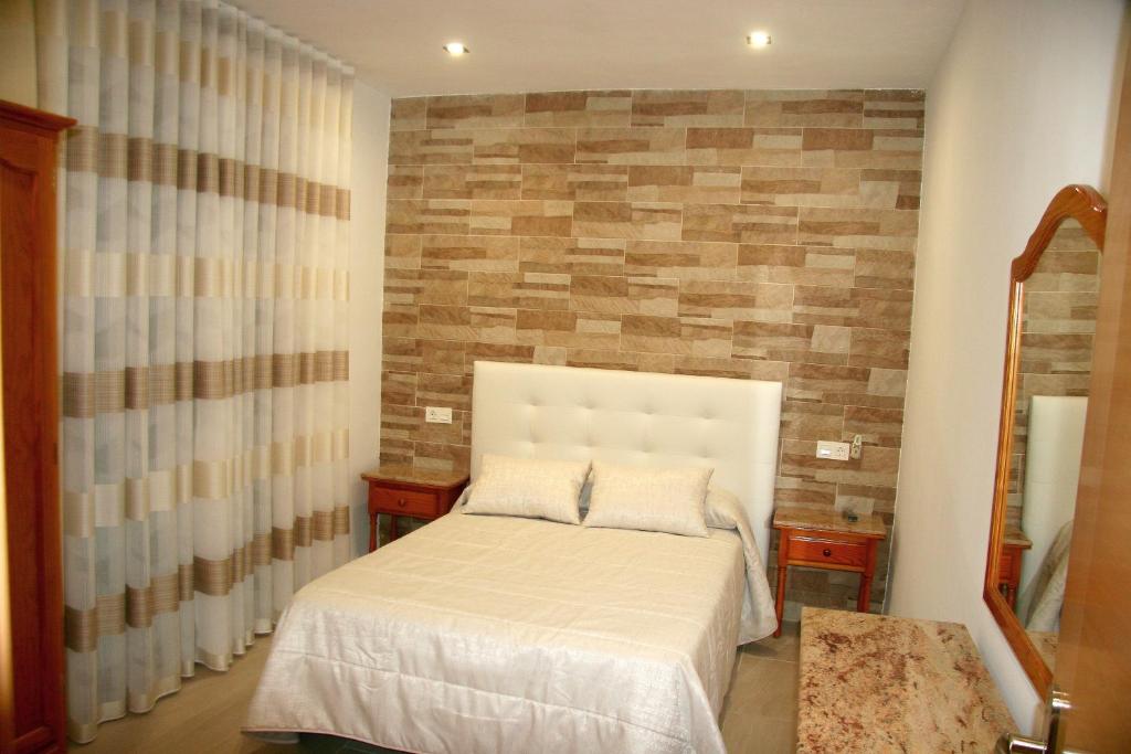 a bedroom with a bed and a brick wall at Hostal Restaurante Grela in Pozo Alcón