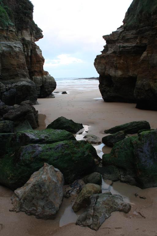 a beach with some rocks and the ocean at Apartamentos Playa Galizano in Galizano