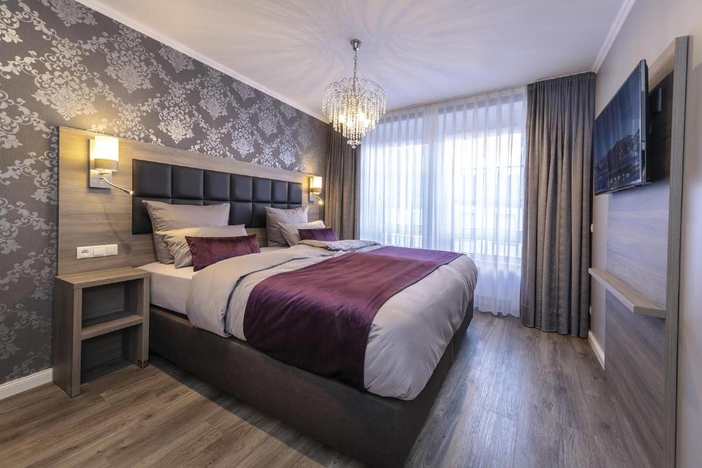 a bedroom with a large bed and a chandelier at Apartmenthaus Burgenheimat in Rhens bei Koblenz in Rhens