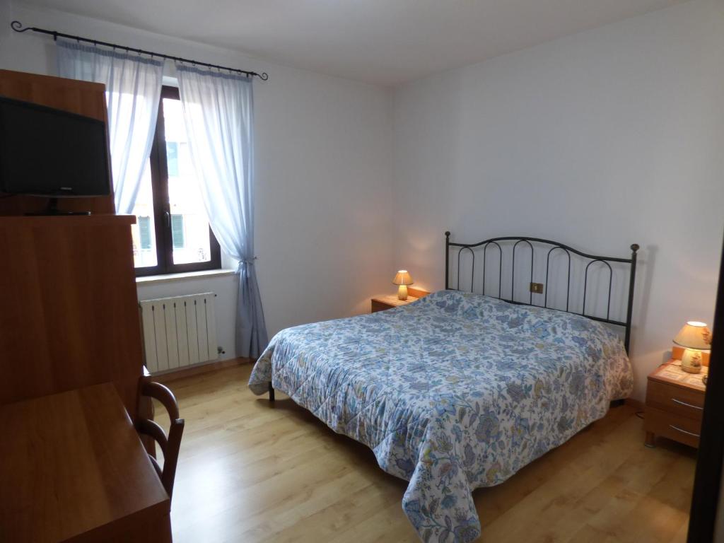 um quarto com uma cama e uma televisão em " Il Bersagliere " Dependance Hotel la Pace em Asciano