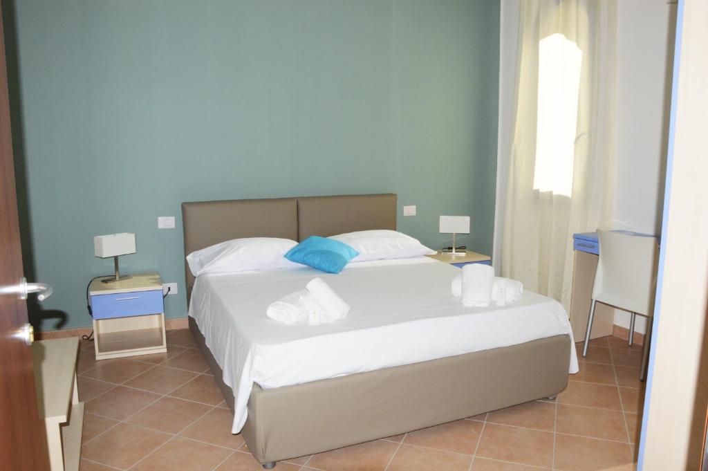 Un dormitorio con una cama blanca con toallas. en Hotel '904, en Buggerru