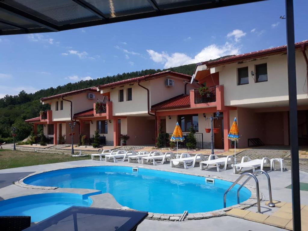 um resort com uma piscina e cadeiras e um edifício em Gledkata Complex em Skobelevo
