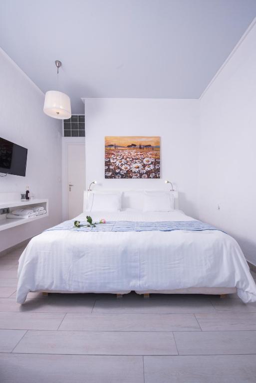 a white bedroom with a white bed and a painting at Aegialis Hotel & Spa in Aegiali