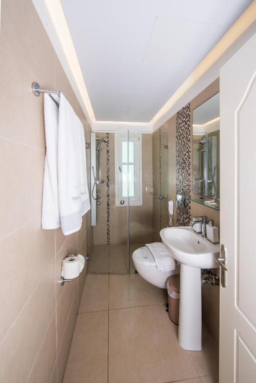 a bathroom with a sink and a toilet and a shower at Aegialis Hotel & Spa in Aegiali