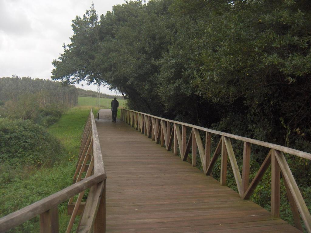 a man walking across a wooden bridge at Apartamentos Playa Galizano in Galizano