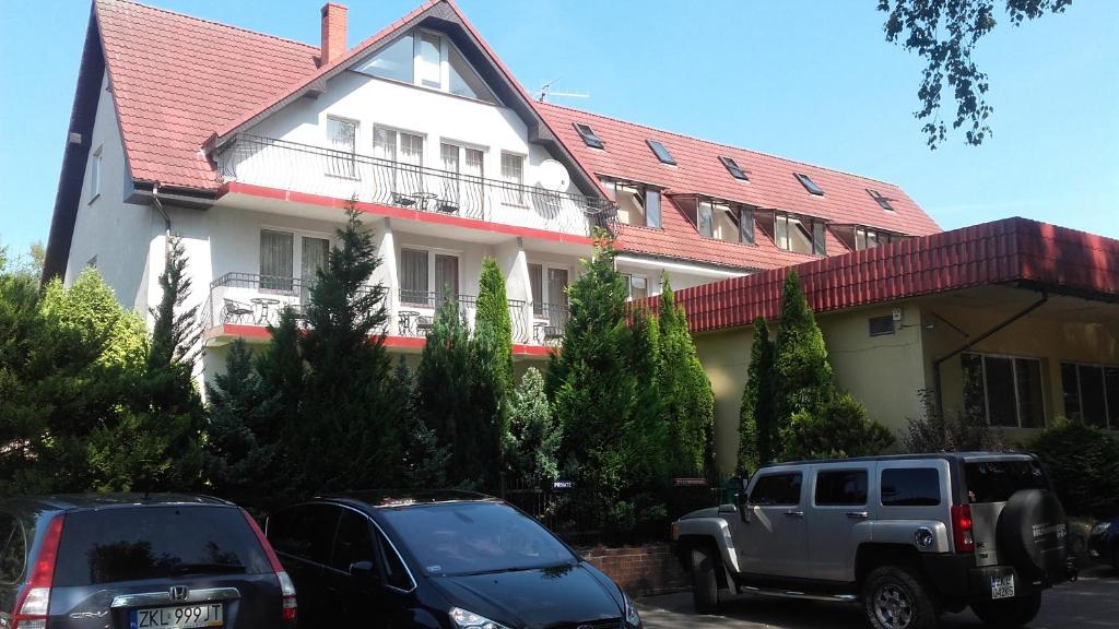 a large house with cars parked in front of it at Anker - Podczele in Kołobrzeg