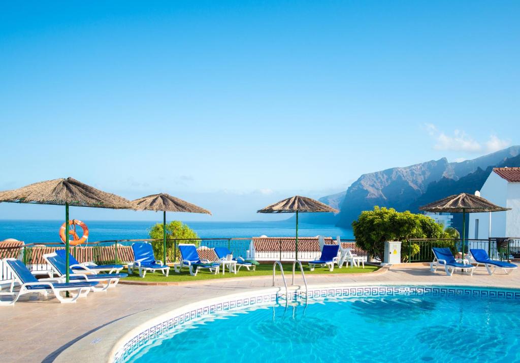 une piscine dans un hôtel avec des chaises et des parasols dans l'établissement Ona Las Rosas, à Puerto de Santiago
