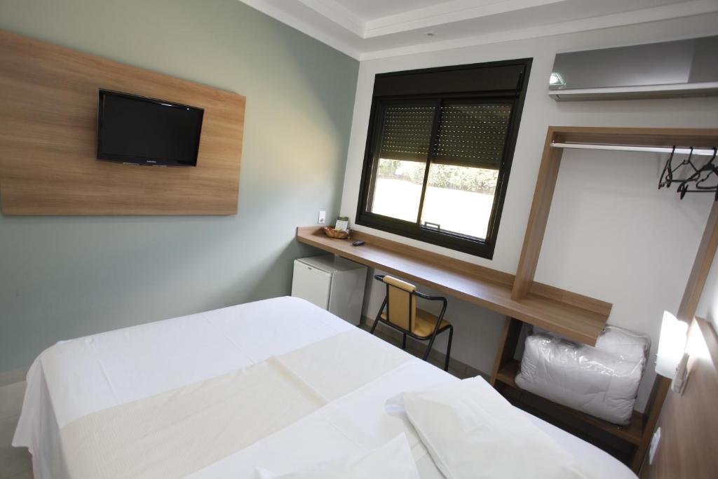 a bedroom with a white bed and a window at Hotel Recreio São Jorge in Jaboticabal