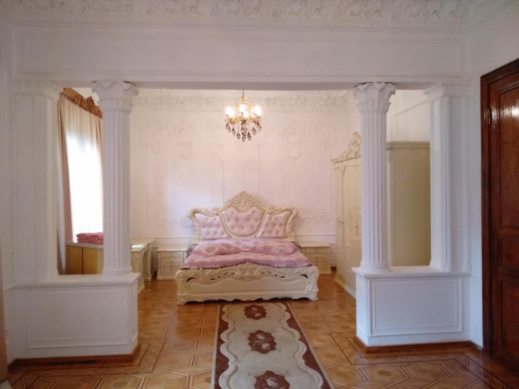 a bedroom with a bed with a chandelier and columns at Hotel Royal in Kutaisi