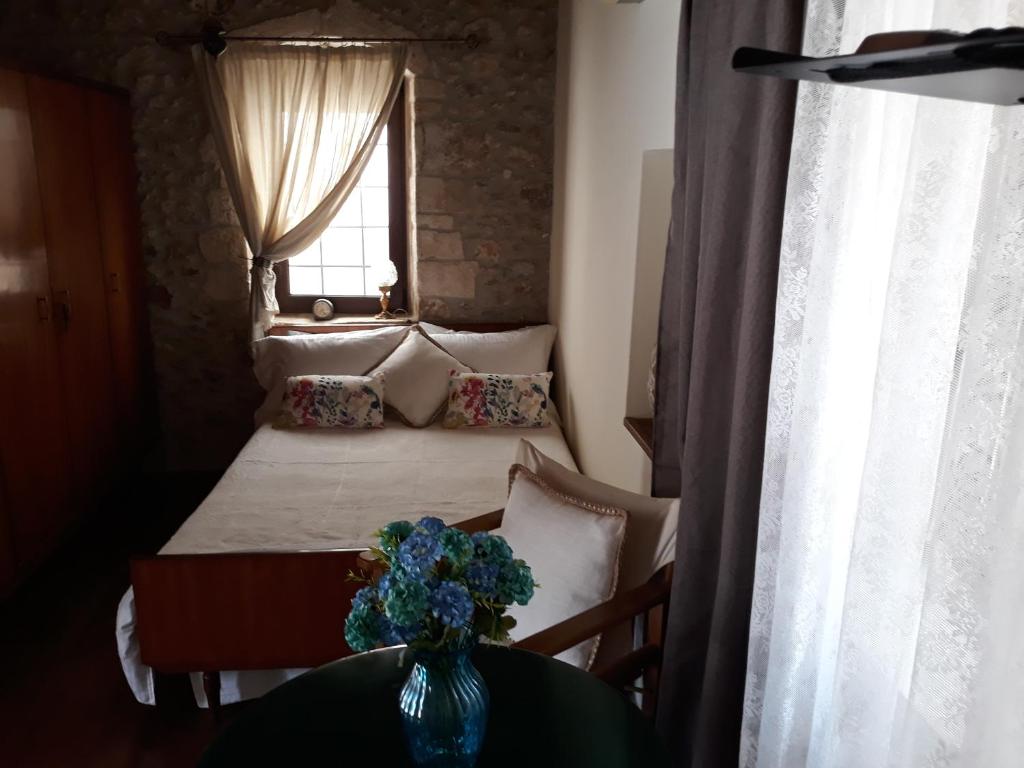 een slaapkamer met een bed met een vaas met bloemen op een tafel bij Koutouloufari Cosy Cretan Cottage in Chersonissos