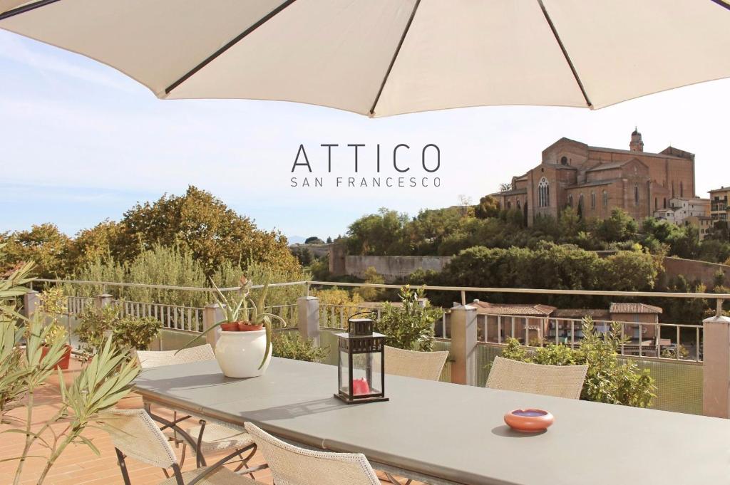 una mesa con sombrilla en el balcón en Attico San Francesco, en Siena