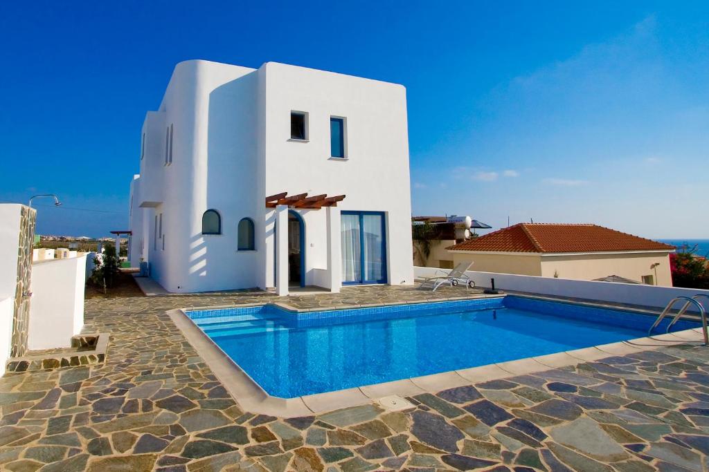 a white house with a swimming pool in front of it at Meltemi Villas in Paphos City