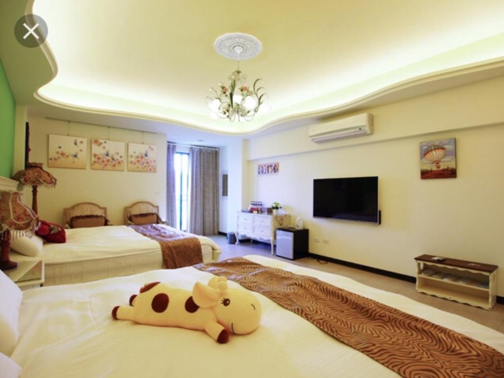a bedroom with two beds with a stuffed cow laying on the bed at 來嘉小棧 in Chiayi City
