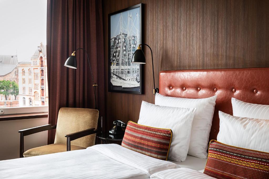 ein Hotelzimmer mit einem Bett, einem Stuhl und einem Fenster in der Unterkunft AMERON Hamburg Hotel Speicherstadt in Hamburg