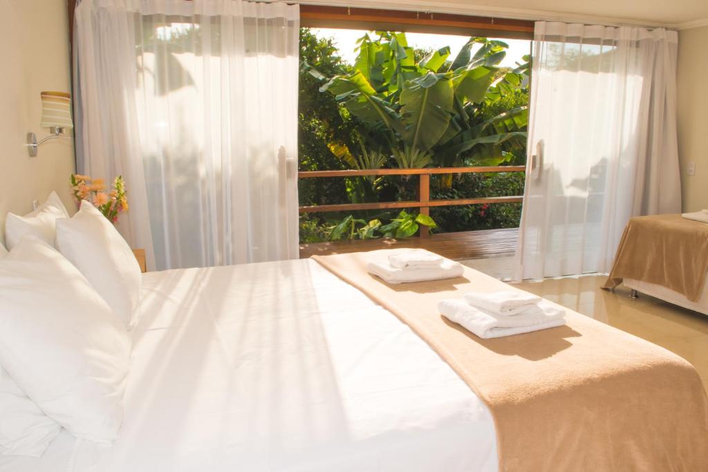 a white bed with two towels on top of it at Pousada Blue Ocean in Búzios
