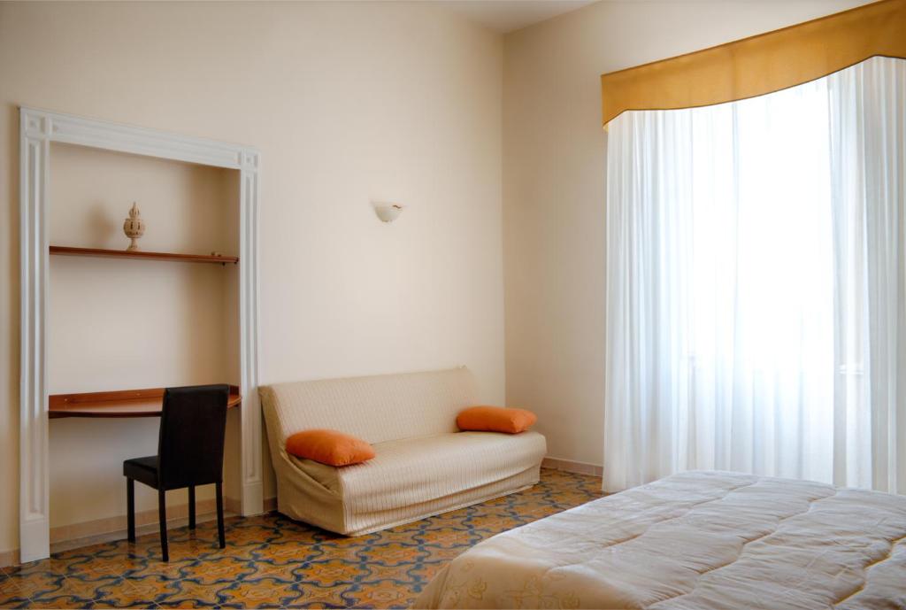 a bedroom with a bed and a chair and a window at Bed and Breakfast Sommavesuvio in Pollena Trocchia