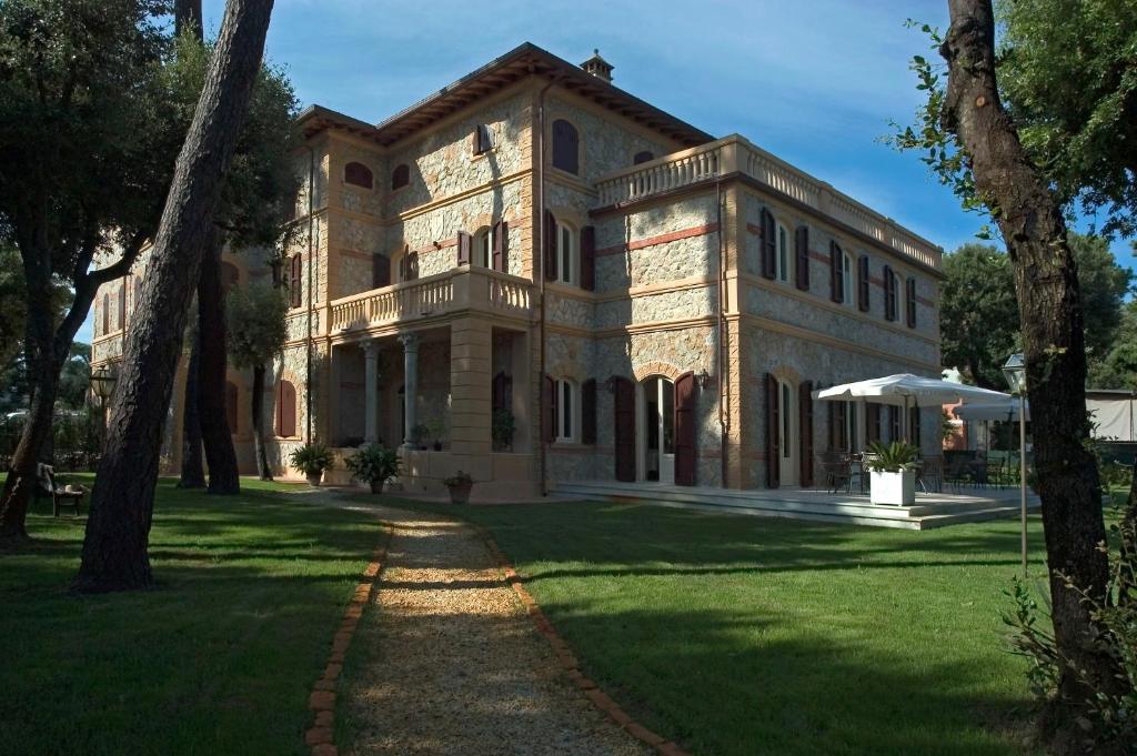 um grande edifício de pedra com árvores em frente em Villa Signori em Marina di Pietrasanta