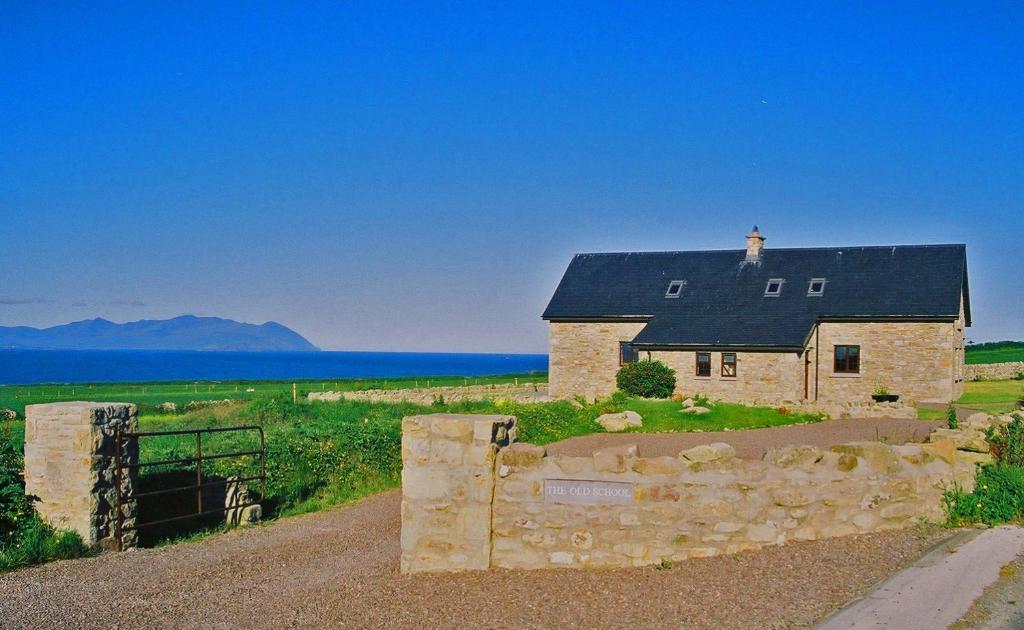 a stone house with a fence in front of it at The Old School in Ballyheigue