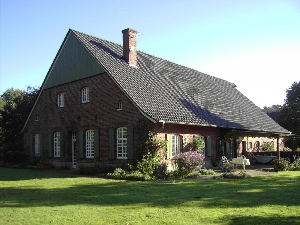 ein großes Backsteinhaus mit schwarzem Dach in der Unterkunft Bauernhof Barlo in Bocholt