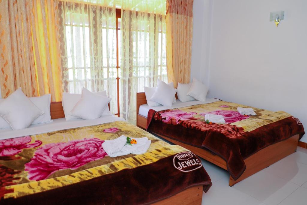 a room with two beds and a window at Oviya Guest in Nuwara Eliya