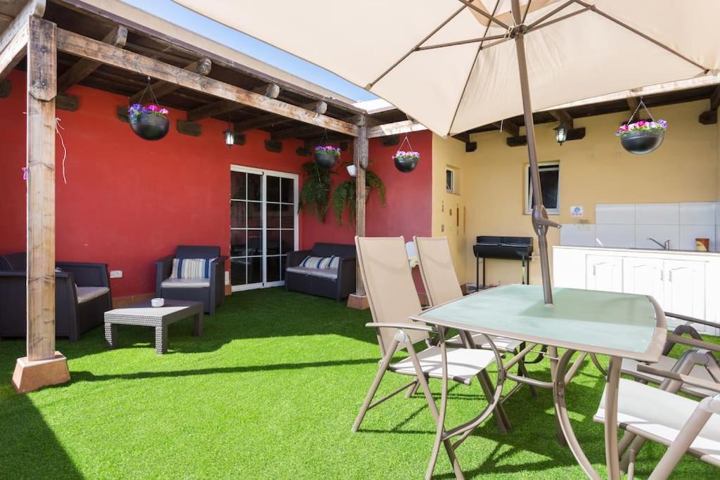 un patio con mesa, sillas y sombrilla en Villa Blanca Tenerife - Private rooms - Terrace and BBQ, 5 minutes from the beach and airport, en San Isidro