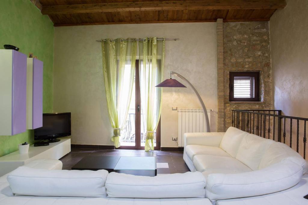 a living room with a white couch and a tv at Il Giardino del Saraceno House in Piazza Armerina