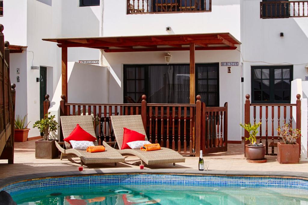 a patio with two chairs next to a swimming pool at Casa Hibiscus in Punta Mujeres