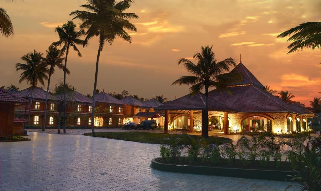 un complejo con palmeras y un edificio en Lakesong Resort en Kumarakom