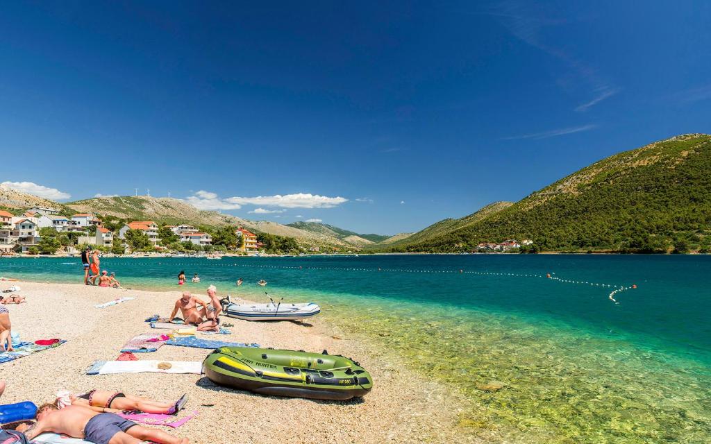a group of people laying on a beach next to the water at Apartments Ana in Grebaštica