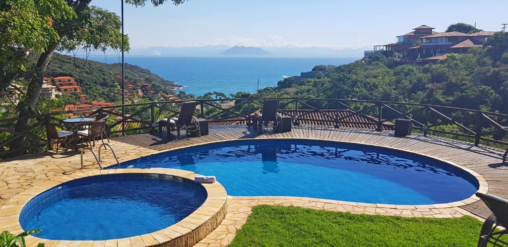 a large swimming pool with a view of the ocean at Pousada Amancay in Búzios