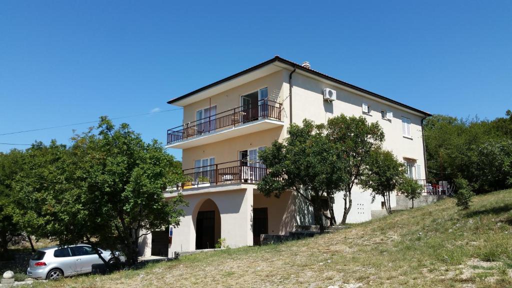 a house on a hill with a car parked in front at Apartments Claudia in Šmrika