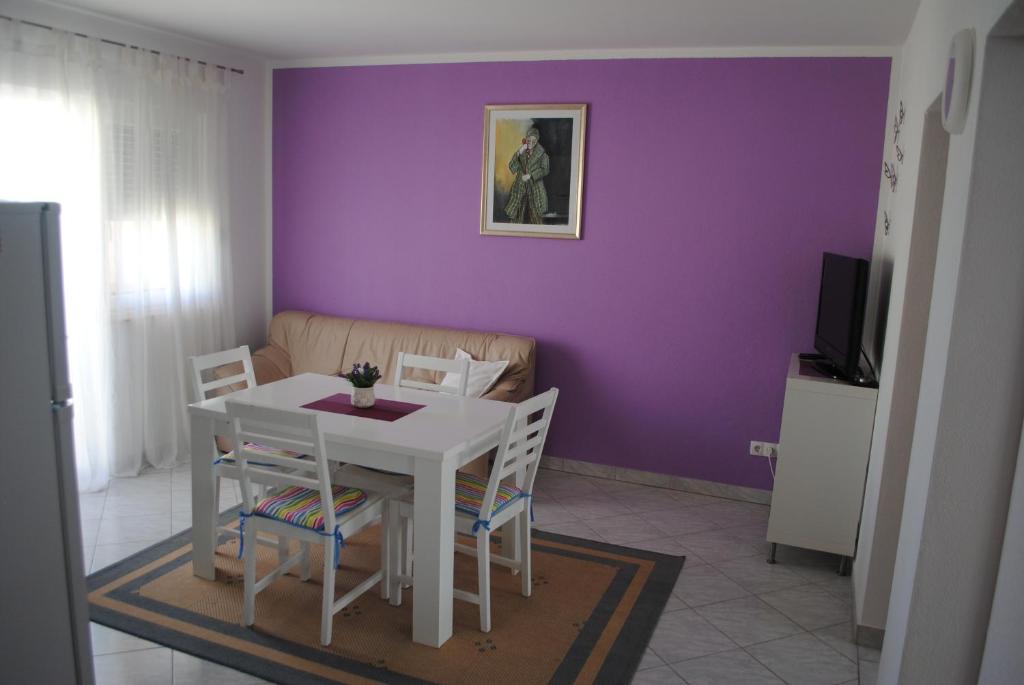 un comedor con una mesa blanca y una pared púrpura en Apartments Vidolma en Povljana