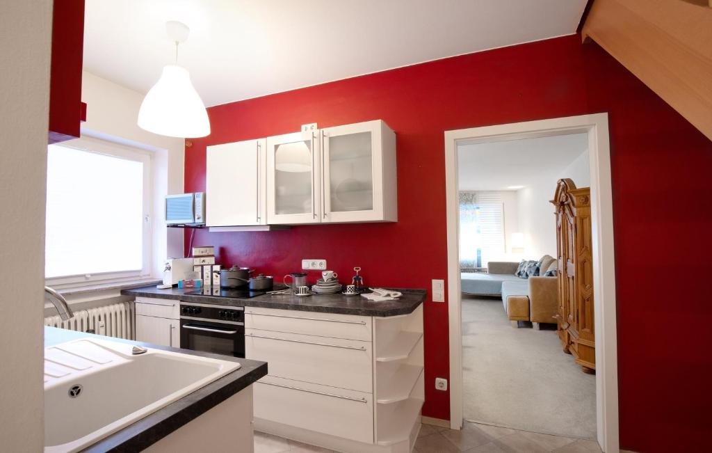 - une cuisine avec des murs rouges, des placards blancs et un évier dans l'établissement Evergreen Chalet, à Garmisch-Partenkirchen