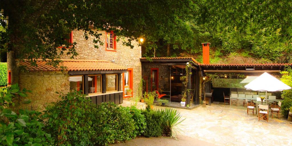 Cette maison dispose d'une terrasse avec une table et un parasol. dans l'établissement A Pontiga I Casa Rural, à Mezonzo