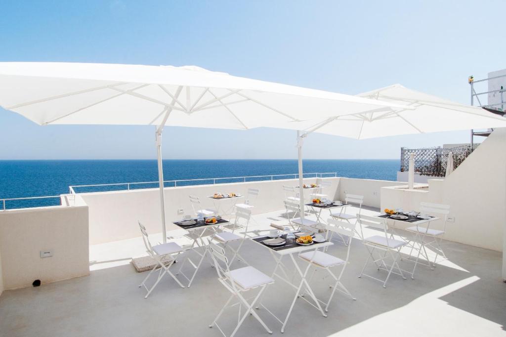 a balcony with white chairs and tables and an umbrella at Dimora Talenti in Polignano a Mare
