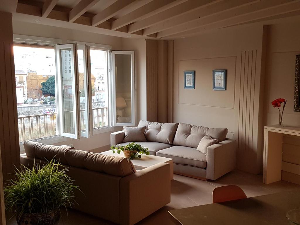 a living room with a couch and a large window at Apartamentos AS Malaga centro historico in Málaga