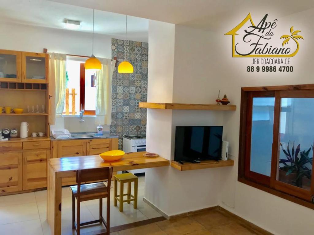 uma cozinha com uma mesa e uma televisão num quarto em Apê do Fabiano em Jericoacoara