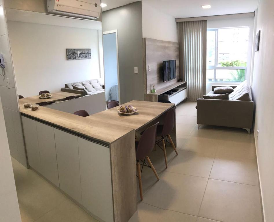 a kitchen and living room with a table and a couch at Apto Promenade I PONTA VERDE in Maceió