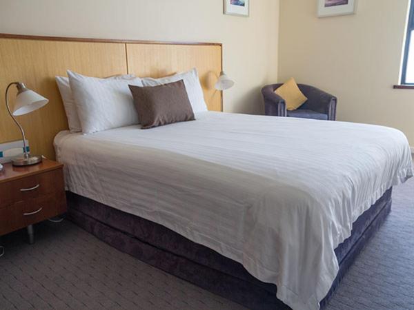 a large bed in a hotel room with a nightstand and a bed sidx sidx at Ocean Beach Hotel in Perth