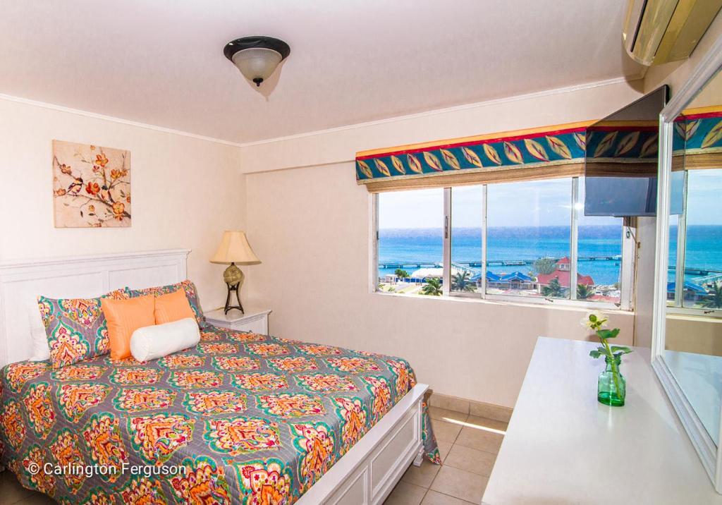 a bedroom with a bed and a view of the ocean at Serenity By The Sea At Turtle Towers in Ocho Rios