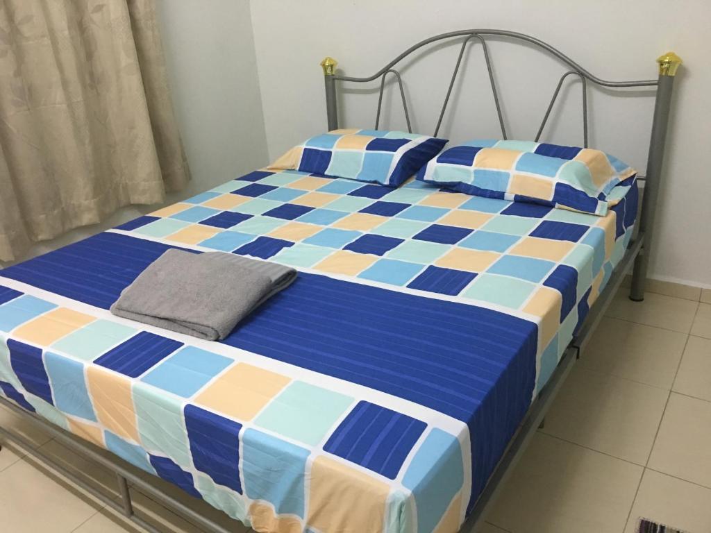 a bed with a blue and orange checkered blanket at Taman Rambai Utama Homestay in Malacca