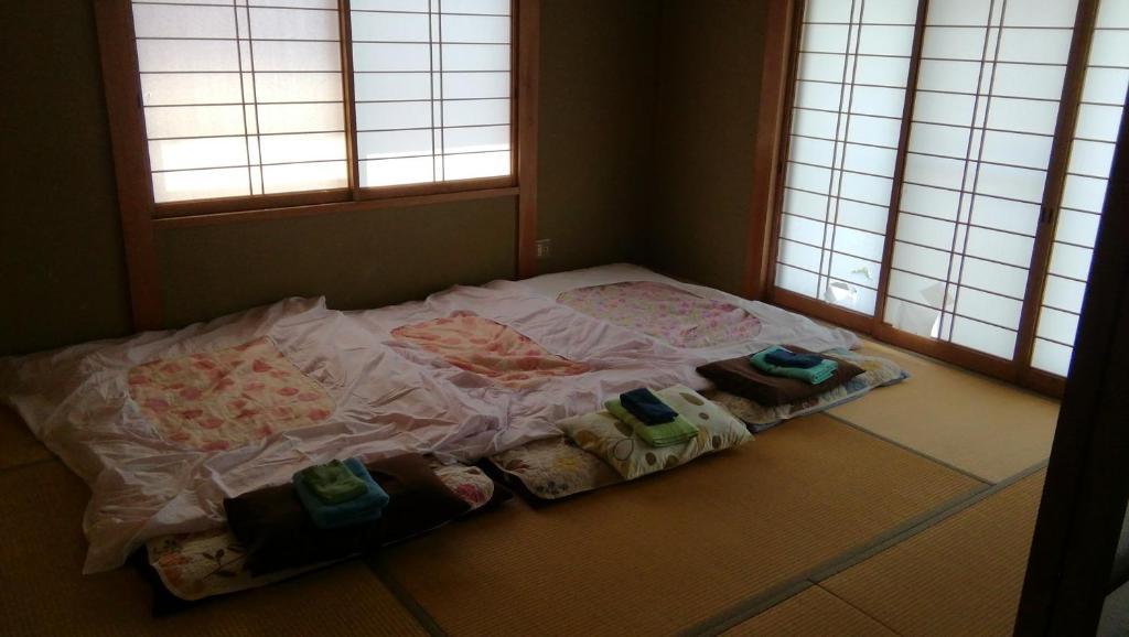 a bed with three pillows on the floor in a room at Nobu Guest House in Kanayama