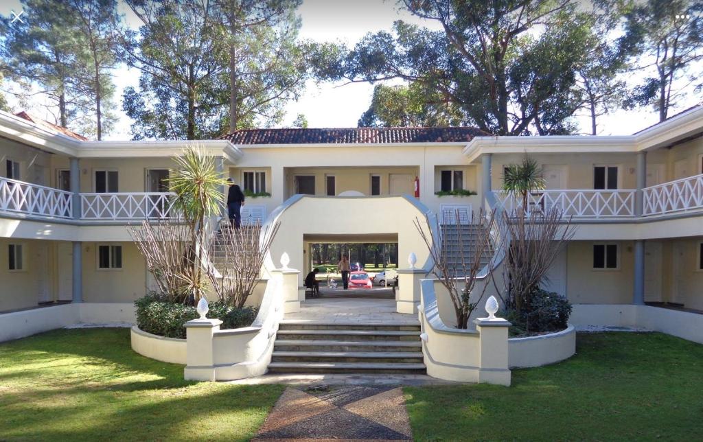 uma grande casa branca com uma escada no quintal em Apartamento Forest Lagoon Punta Del Este em Punta del Este