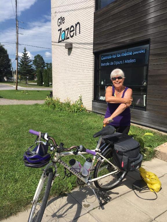 a woman sitting on a bike in front of a building at Gîte Zazen in Mont-Laurier