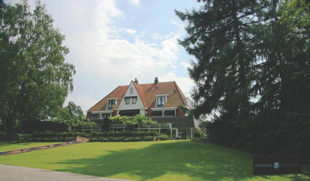 una casa grande con un césped verde delante de ella en Fletcher Hotel Restaurant Sallandse Heuvelrug en Rijssen