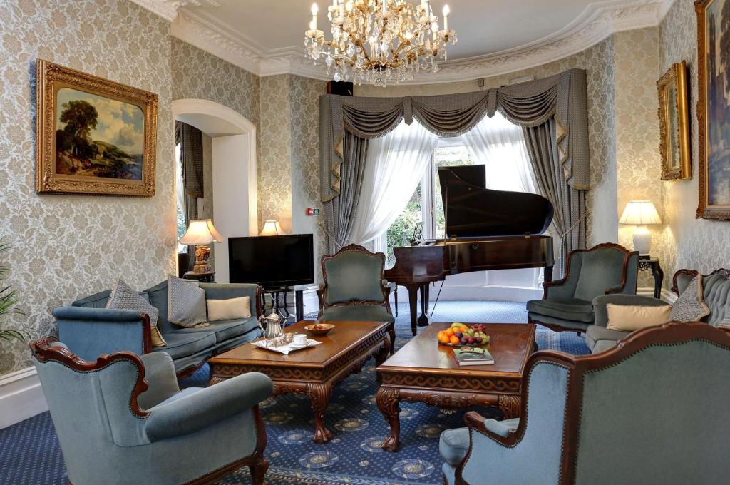 a living room with a piano and a living room with chairs at Best Western Swiss Cottage Hotel in London