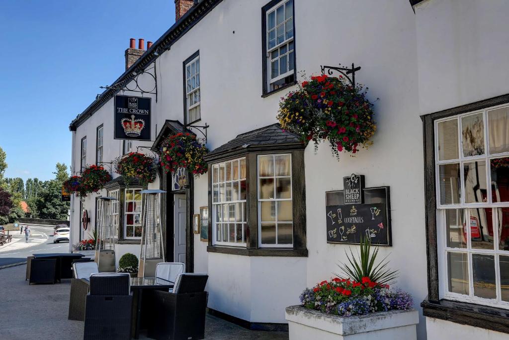 a white building with windows and flowers on it at The Crown Hotel, Boroughbridge, North Yorkshire in Boroughbridge
