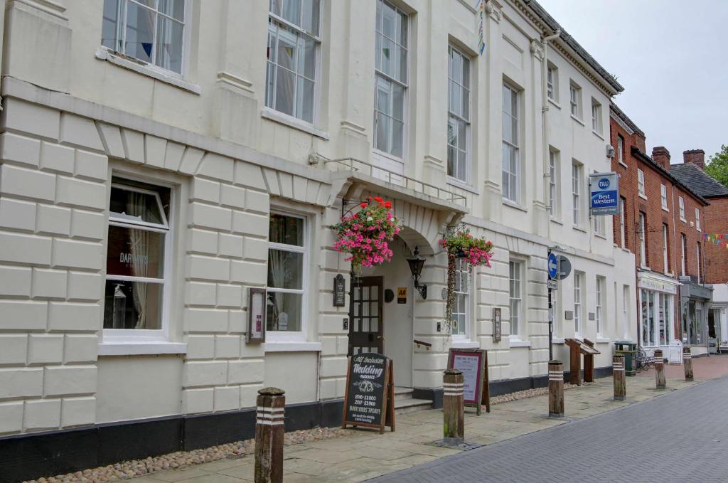 a building with flowers on the side of a street at Best Western Lichfield City Centre The George Hotel in Lichfield