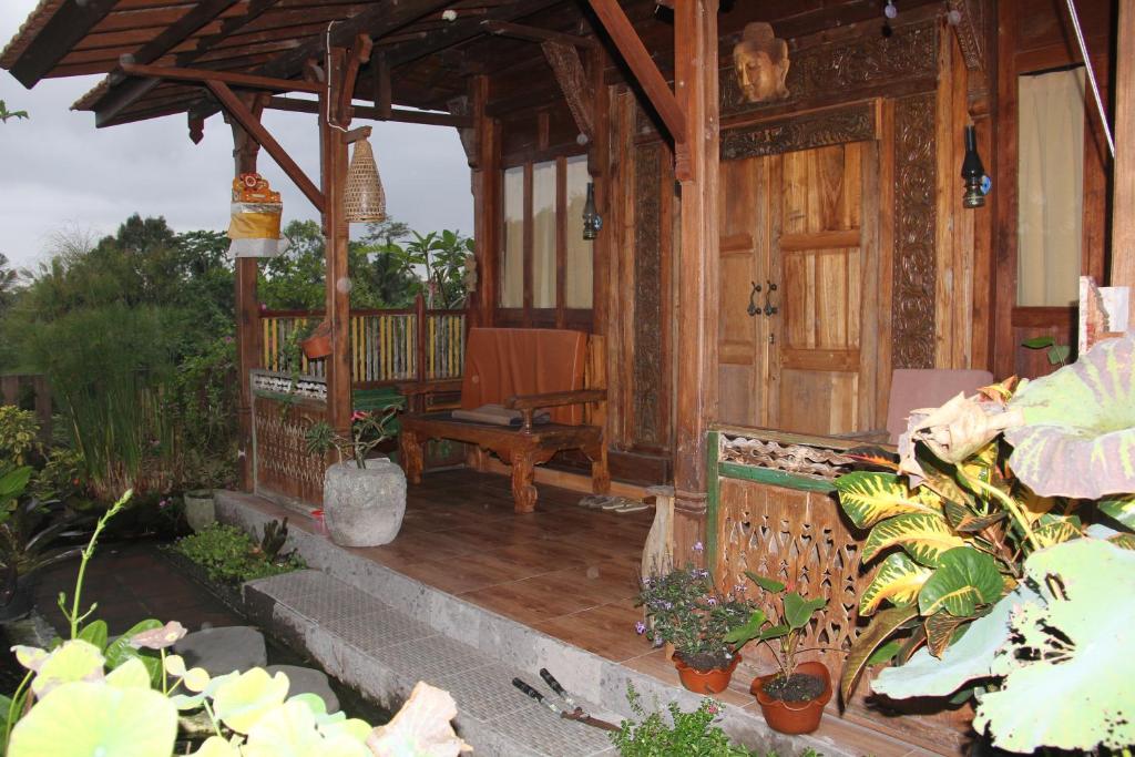 une terrasse couverte d'une maison avec un banc et des plantes dans l'établissement Ogek Home Stay, à Ubud