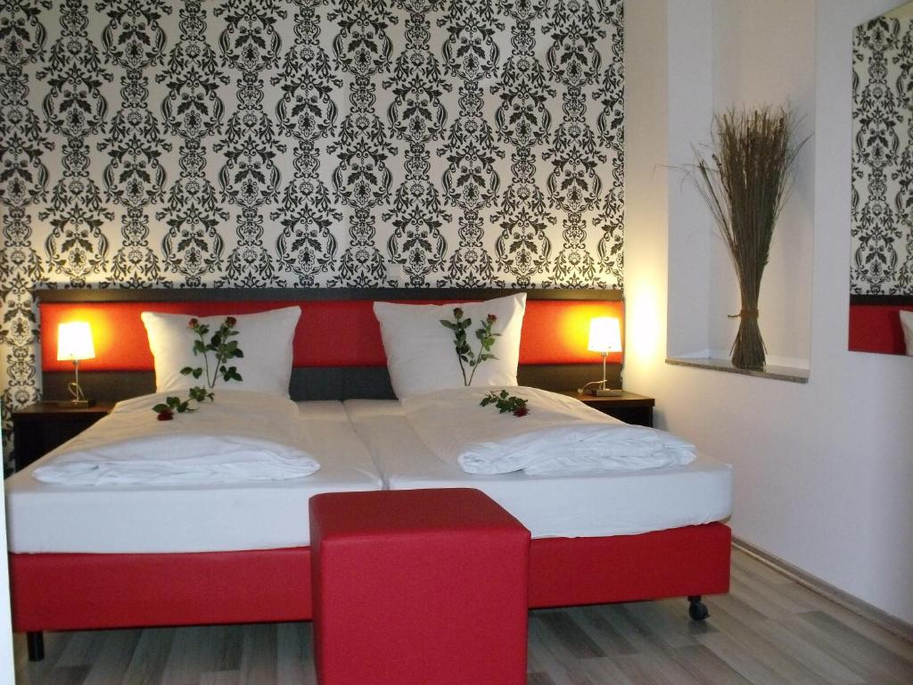 a bedroom with a large bed with a red headboard at Cityhotel Ahlen Garni in Ahlen